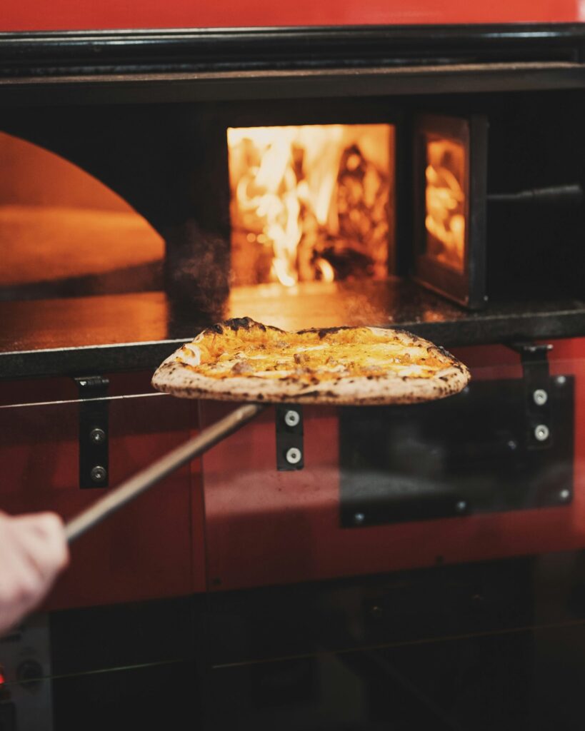 薪ストーブにピザを入れる