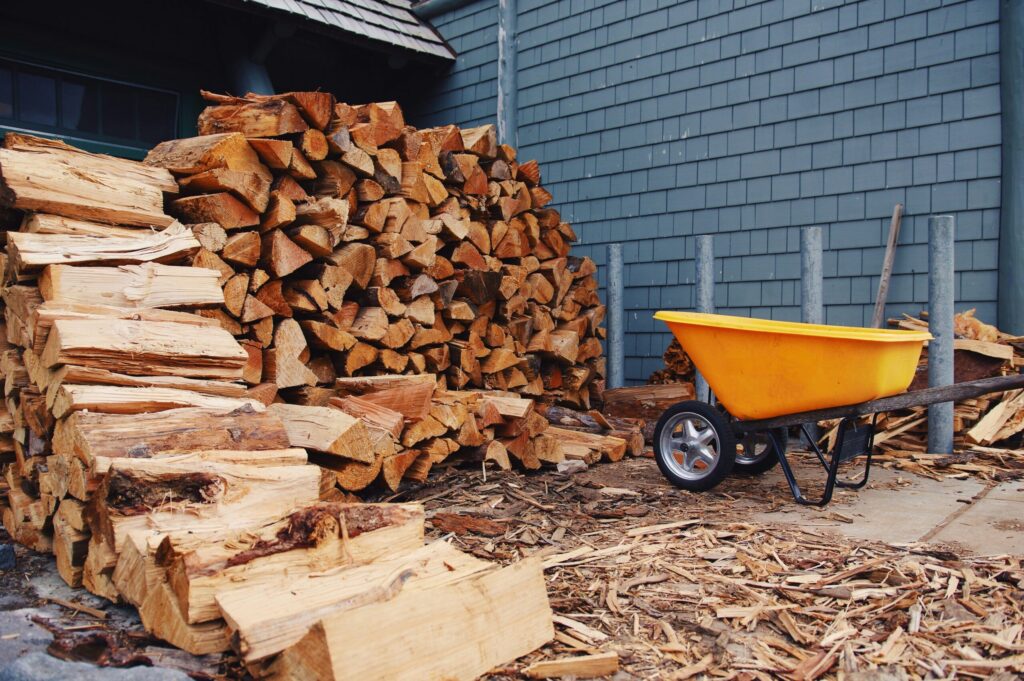 丸太の山の隣にある木でいっぱいの手押し車