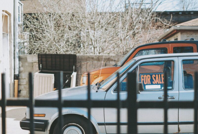 茶色の建物の近くに駐車された青い車