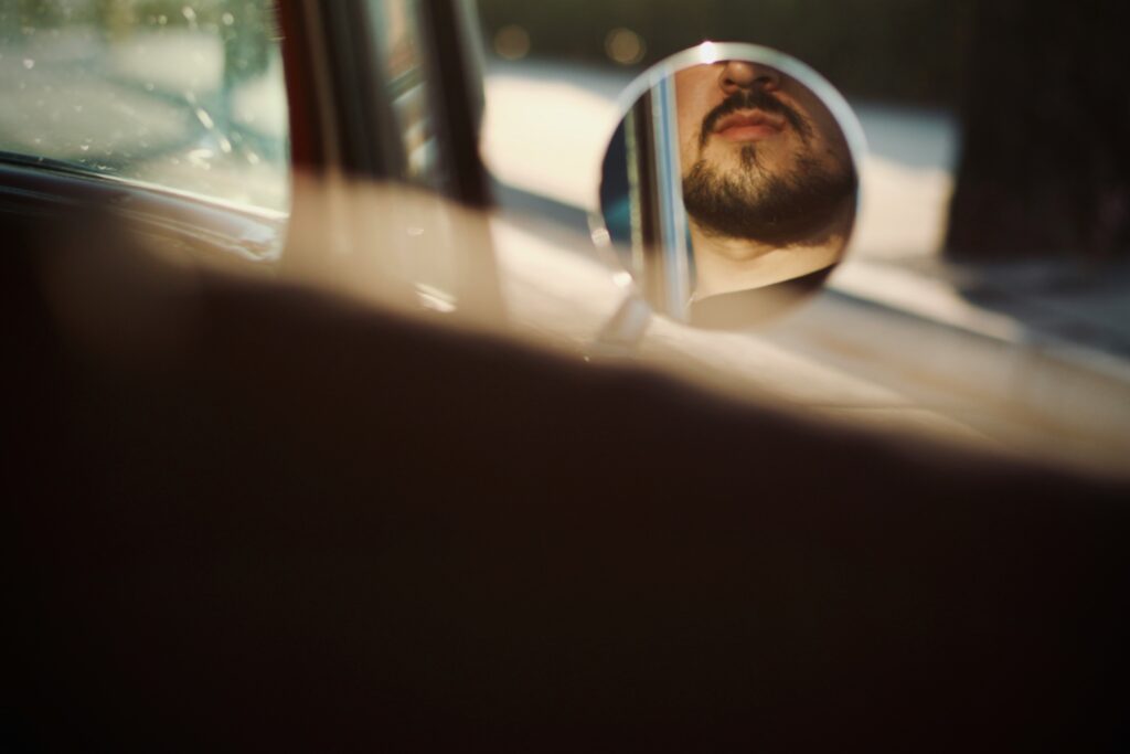 昼間、車の窓を眺める黒いサングラスの男